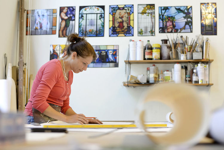 Woman working on draft in glazier's workshop