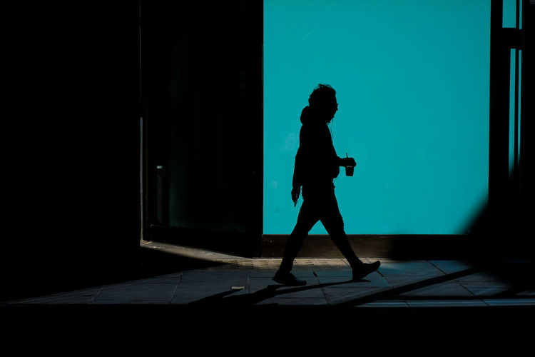 Side view silhouette of a man walking with a drink