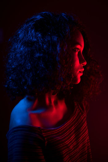 Close-up portrait of young woman against black background