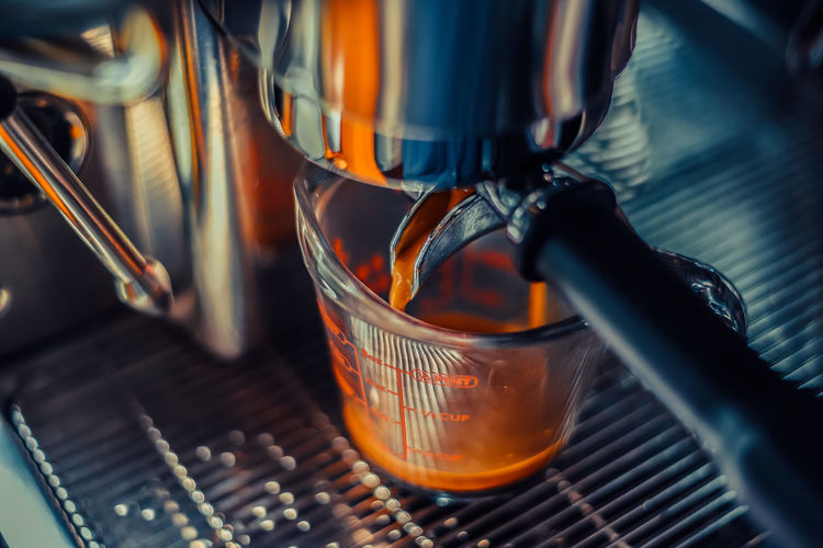 Barista making an americano shot coffee , machine into cup glass, close-up