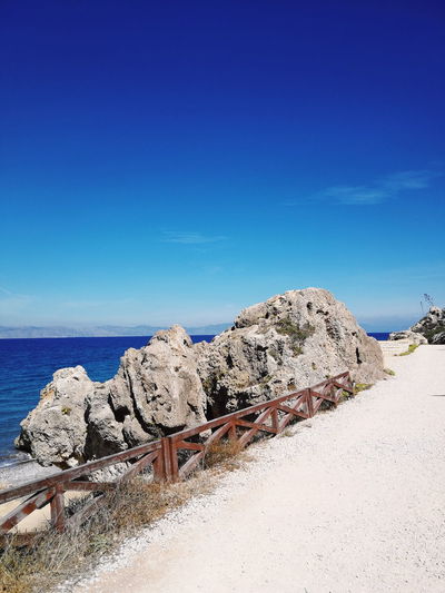 Scenic view of rocky beach against clear blue sky