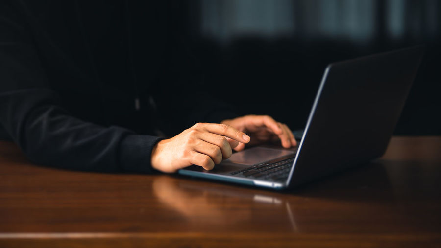 Midsection of businessman using laptop on table