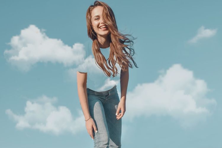 Portrait of happy woman standing against sky