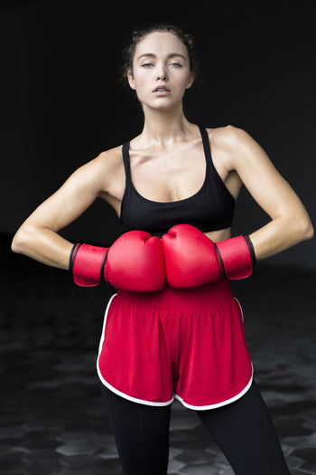 Confident female athlete wearing boxing gloves standing at basement