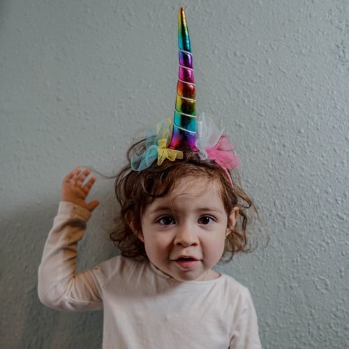 Portrait of cute girl wearing unicorn hat while standing against wall
