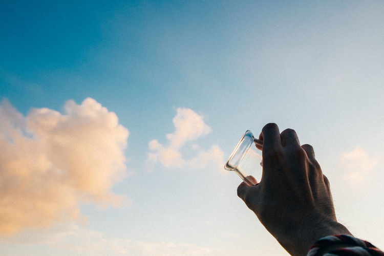 Low angle view of man with glass against sky