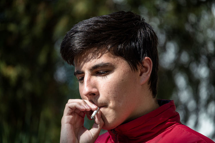 Young man looking down while smoking cigarette