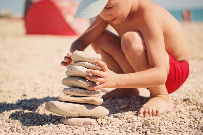 Boy playing with stones at beach