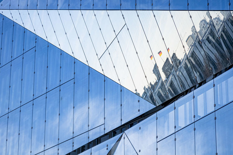 Low angle view of glass building against blue sky
