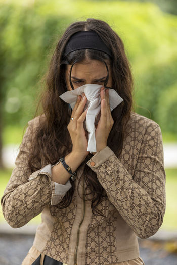 Teen girl with cold blowing her runny nose with tissue. portrait teenager get sick sneezing from flu