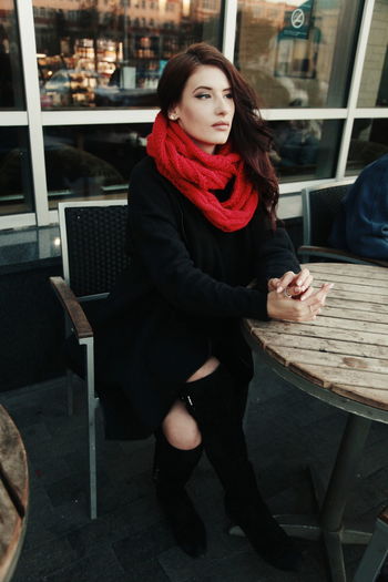 Beautiful woman wearing scarf sitting at table outside cafe