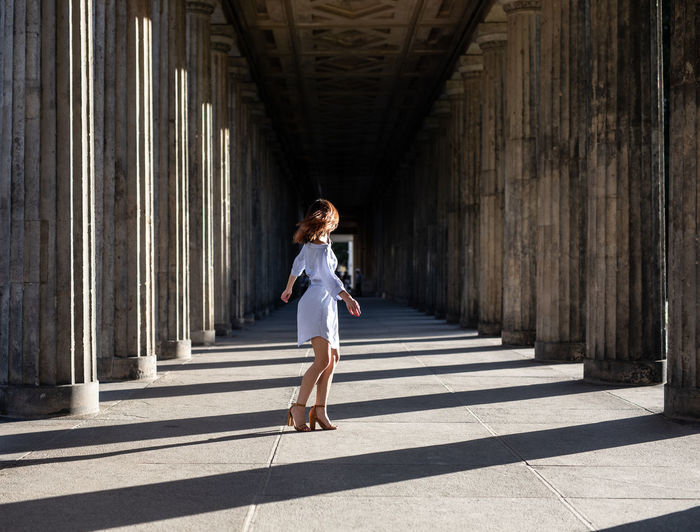 Side view of woman standing at colonnade