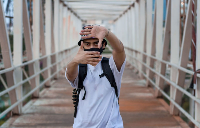 Man photographing with mobile phone standing on railing