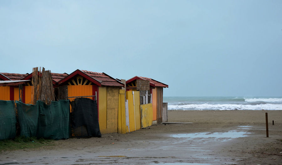 Beach hut by sea against clear sky