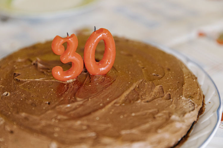 Delicious homemade birthday cake with candles in shape of 30 on table
