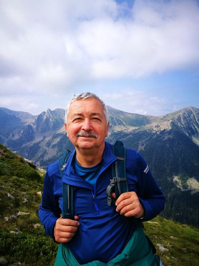 Portrait of smiling man standing on mountain against sky