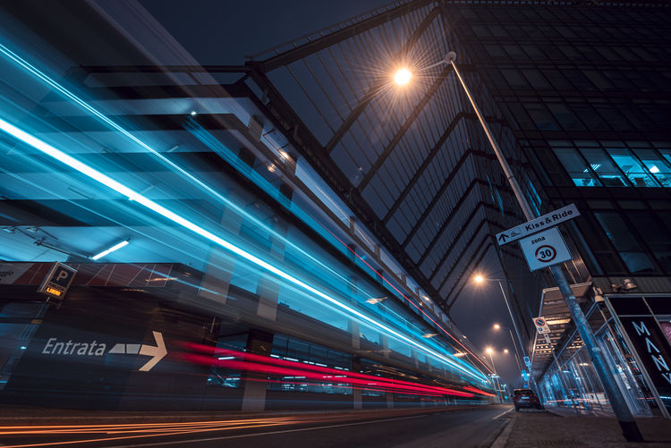 Light trails between modern buildings. night photography. electric blue and transportation.