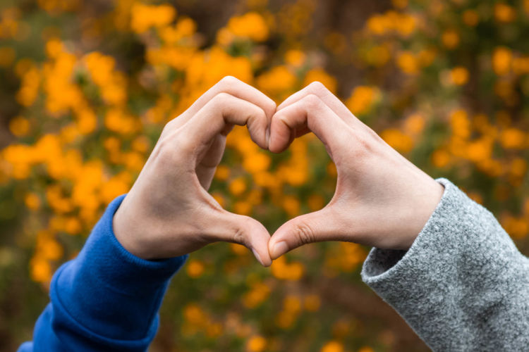 Midsection of man making heart shape against plants
