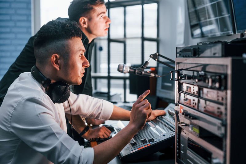 Conception of teamwork. two guys is indoors in the radio studio is busy by broadcast.