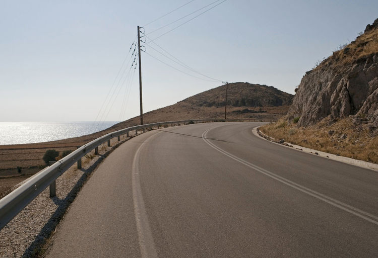 Road leading towards sea against clear sky
