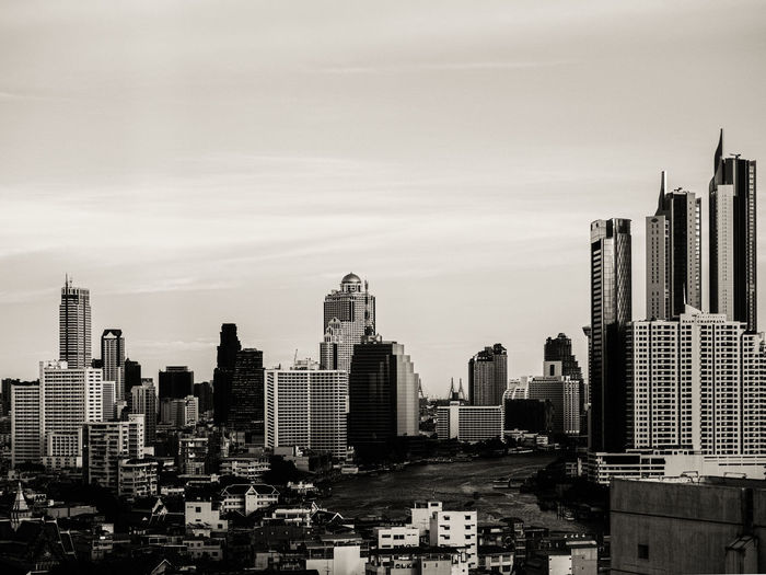 Bangkok city skyline with skyscrapers and chao phraya river under clear sky in sepia tone monochrome