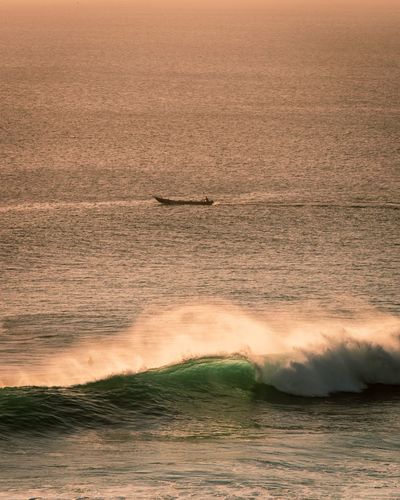 Native fishing boat and beautiful wave off the coast of uluwatu in bali indonesia during sunset