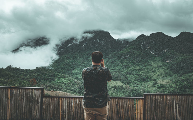 Rear view of man looking at mountains against sky