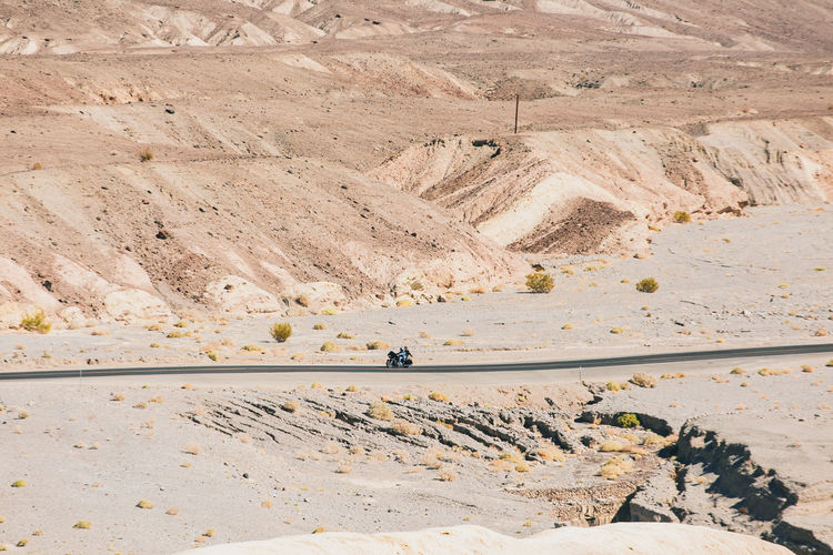 People riding motorcycle on road amidst desert