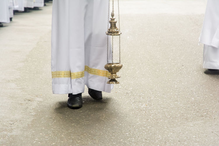Priest is using a thurible to exhale incense during the corpus christ procession 