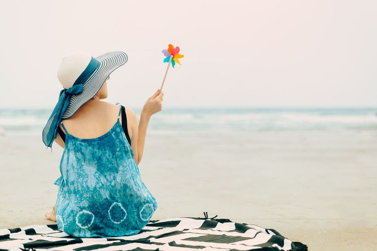 Midsection of woman with umbrella on beach against sea