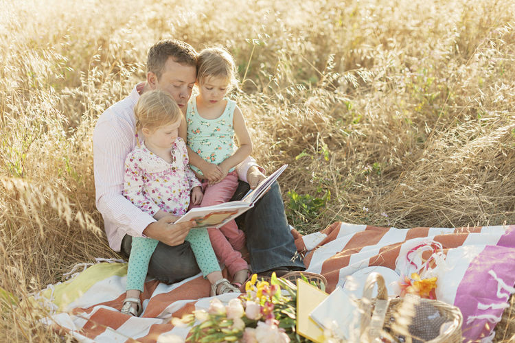 Father reading book to daughters