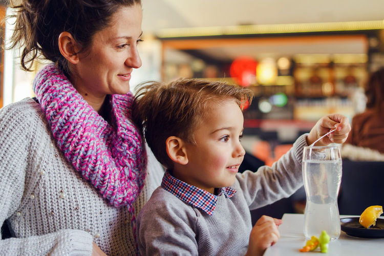 Smiling woman sitting with son at table in restaurant