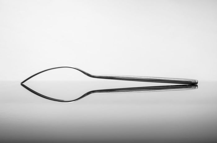 Close-up of fork with reflection against white background