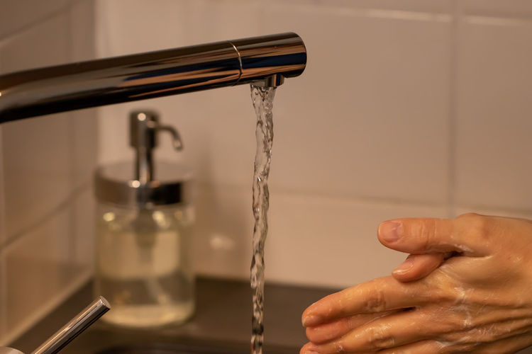 Midsection of person holding faucet at home