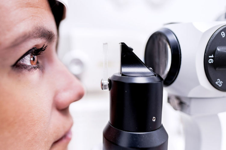 Closeup female patient with eye illuminated with light waiting for tonometer to finish measure intraocular pressure during eye examination in clinic