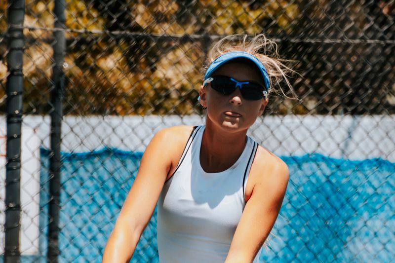 Young female tennis player with wind blown blonde hair amd sunglasses