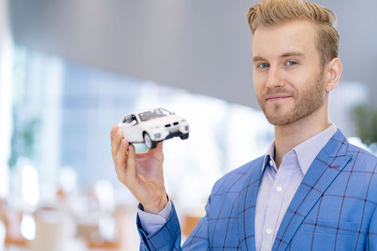 Portrait of businessman holding toy car