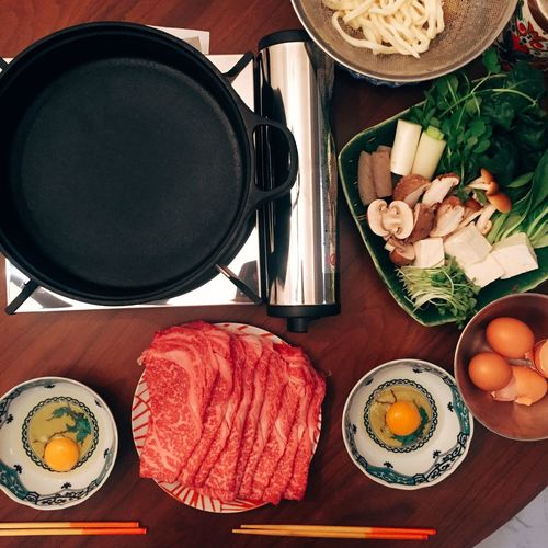 Directly above food ingredients with cooking pan and stove on table
