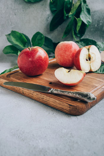 Front view of freshly harvested ripe red organic apples on wooden cutting board on table 