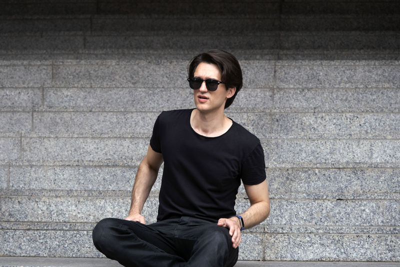 Young man sitting on wall
