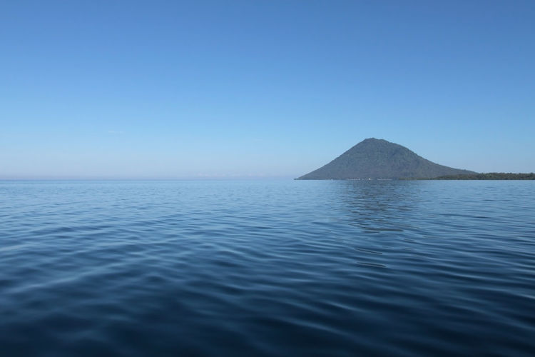 Blue sea and manadotua island on a horizon. bunaken marine park, north sulawesi, indonesia