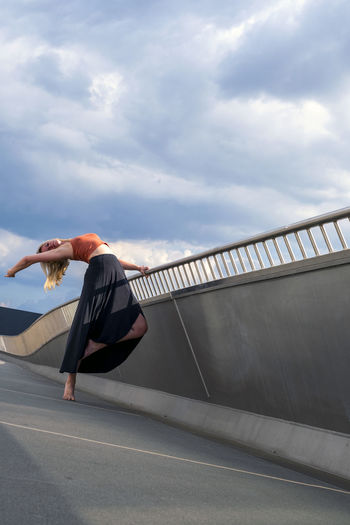 Side view of person skateboarding on bridge against sky