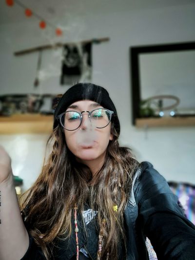 Portrait of young woman smoking at home