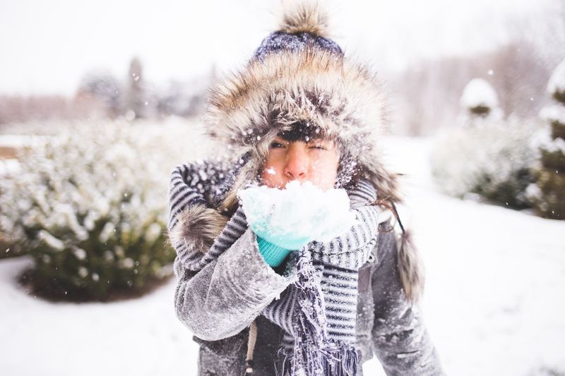 Portrait of girl blowing snow during winter