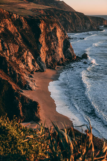 High angle view of cliff by sea during sunset