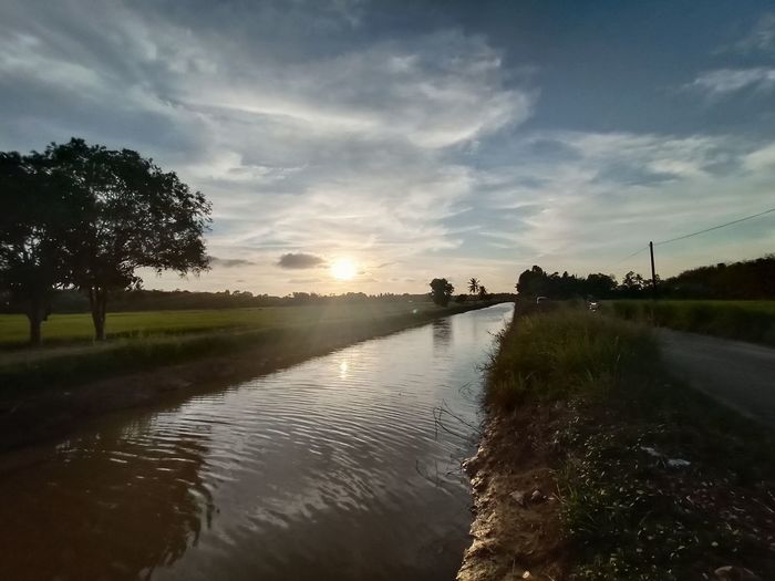 Scenic view of canal against sky during sunset