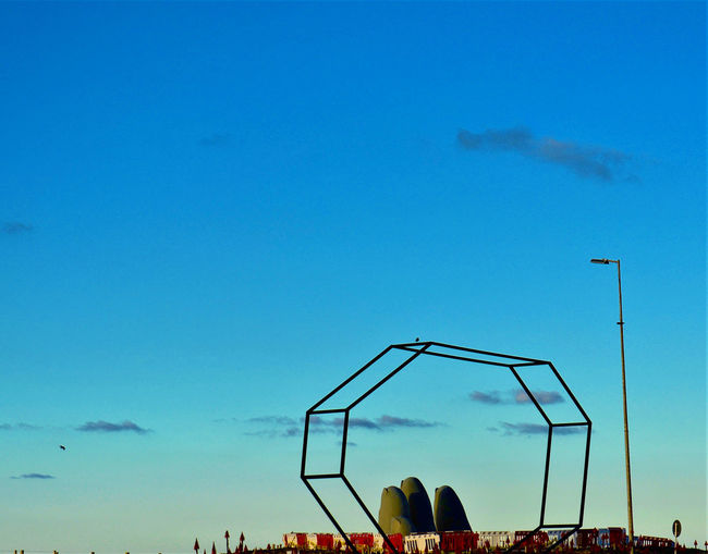 Low angle view of silhouette cranes against blue sky