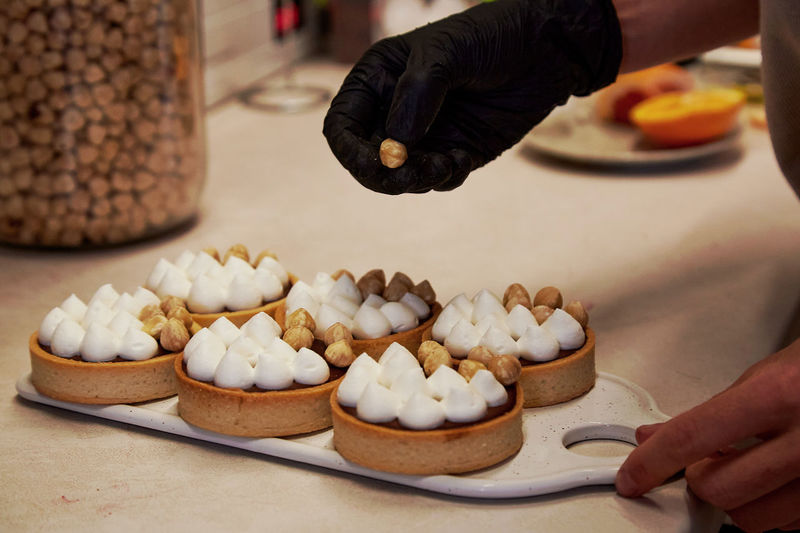 Confectioner is decorating a tarts with nuts in a cafe. french aesthetic hazelnut creamy tarts