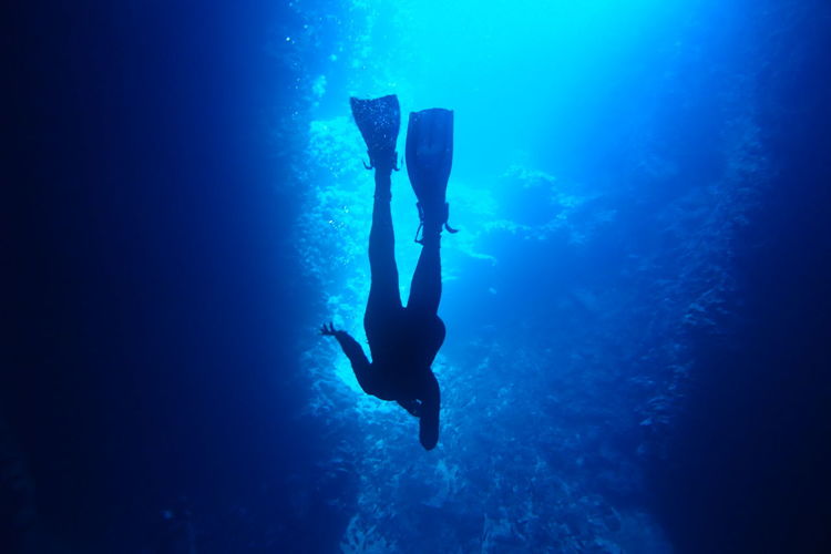 Full length of swimming cave diving silhouette in blue sea waters of vava'u, tonga