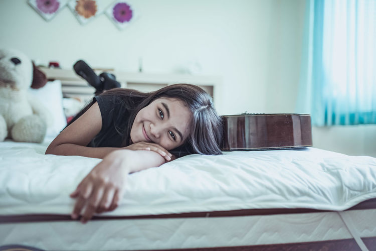 Portrait of smiling woman lying on bed at home